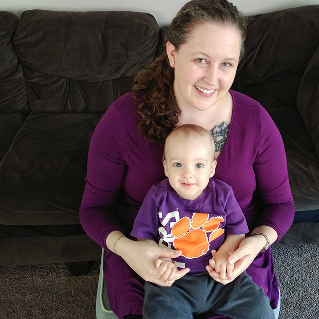 Lupus community advocate Ava Meena and her baby dressed in purple smile at the camera.