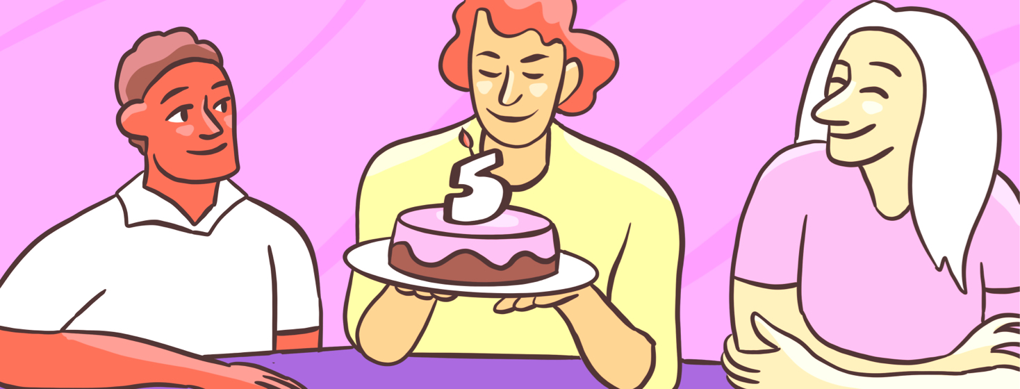 A woman holds a cake with a 5 candle surrounded by smiling friends.