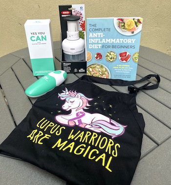 Giveaway set featuring Lupus Warriors Are Magical shirt, anti-inflammatory diet cookbook, electric can opener, Oxo chopper