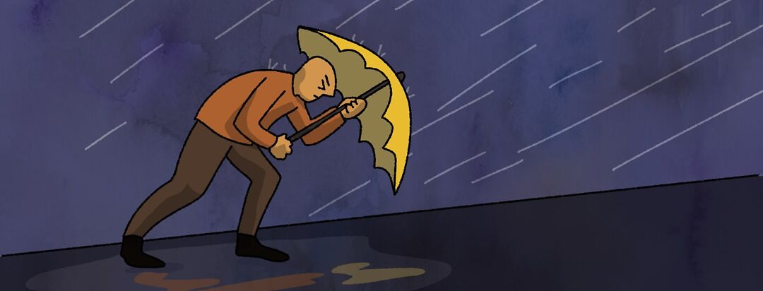 A man walking uphill in a rainstorm against the wind.